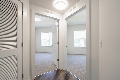 a view of a bedroom from the hallway of a home with white walls and wood