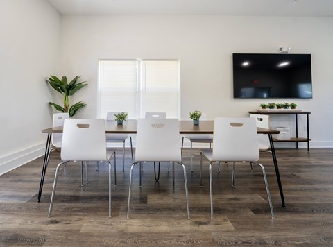 a dining room with a table and chairs and a tv on the wall