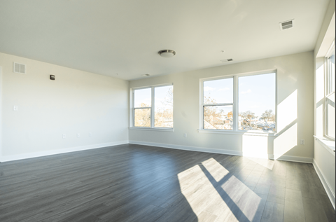 an empty living room with wood floors and windows