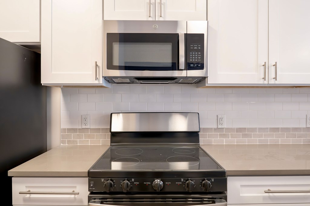 A modern kitchen with a stove top oven and microwave above it.