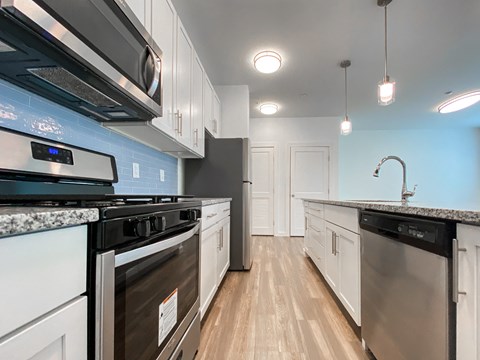 an empty kitchen with white cabinets and stainless steel appliances