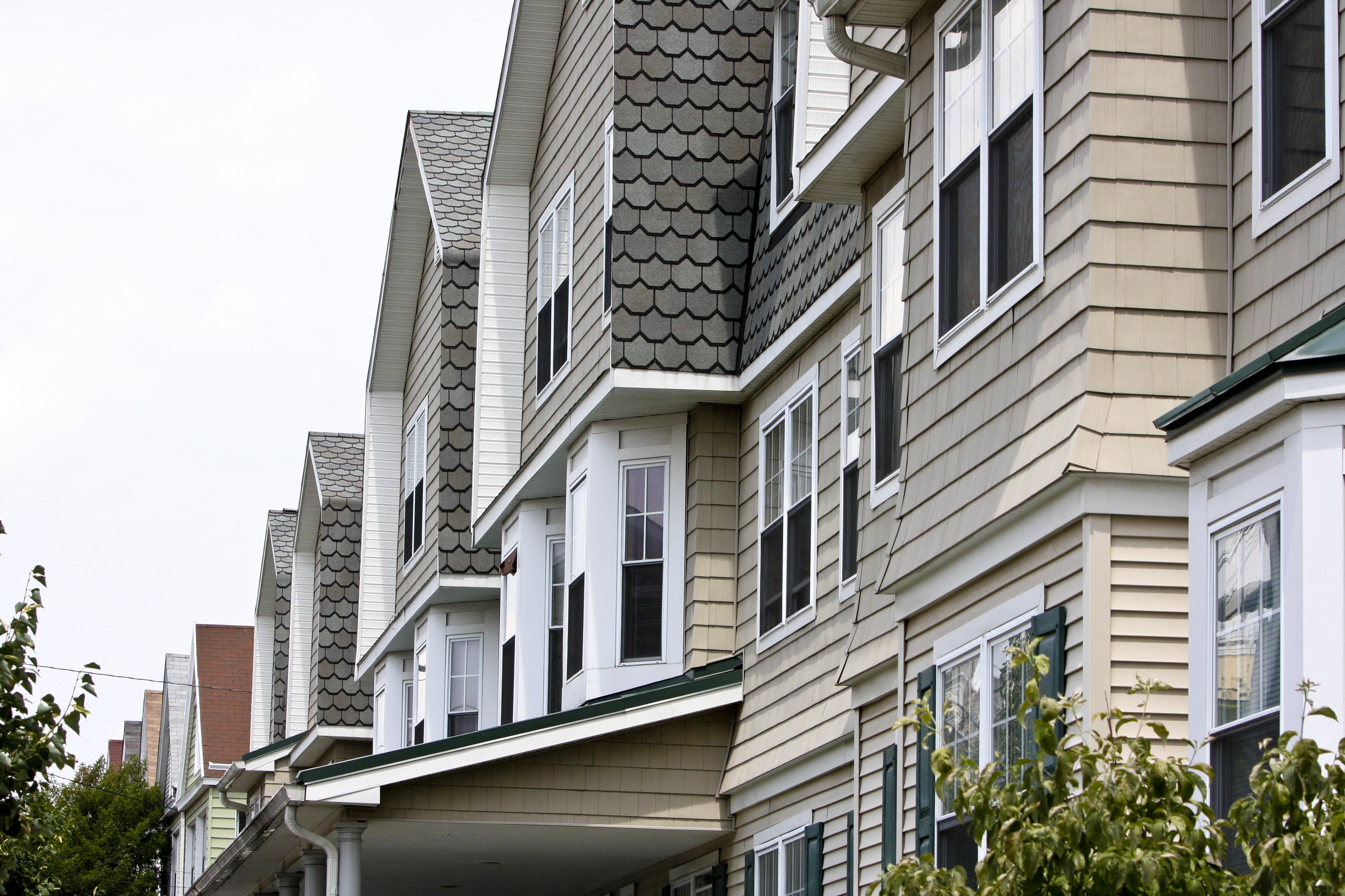 a row of townhomes with vinyl siding and white windows