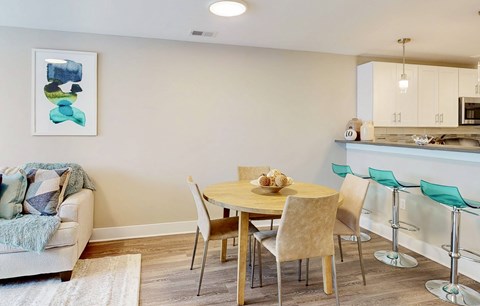 A dining room with a table set for two and a couch with a throw on it.