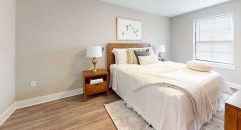A bedroom with a large bed and a nightstand with a lamp.