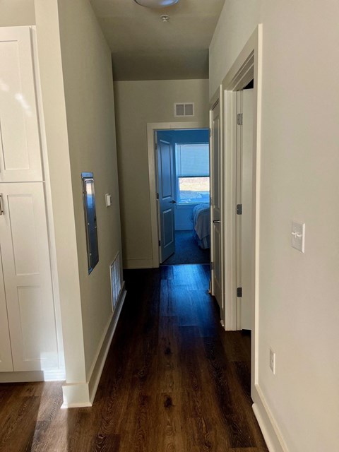 a bedroom with a hallway with wood floors and a bed
