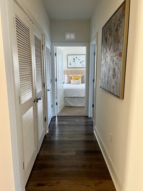 a narrow hallway with a bedroom in the background and a door to a room with