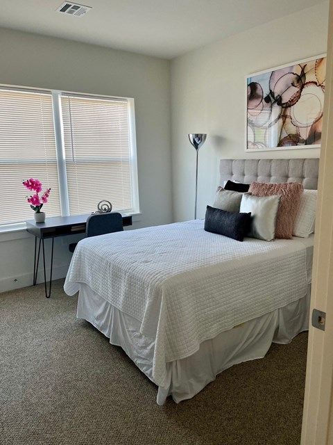 a bedroom with a bed and a desk and a window