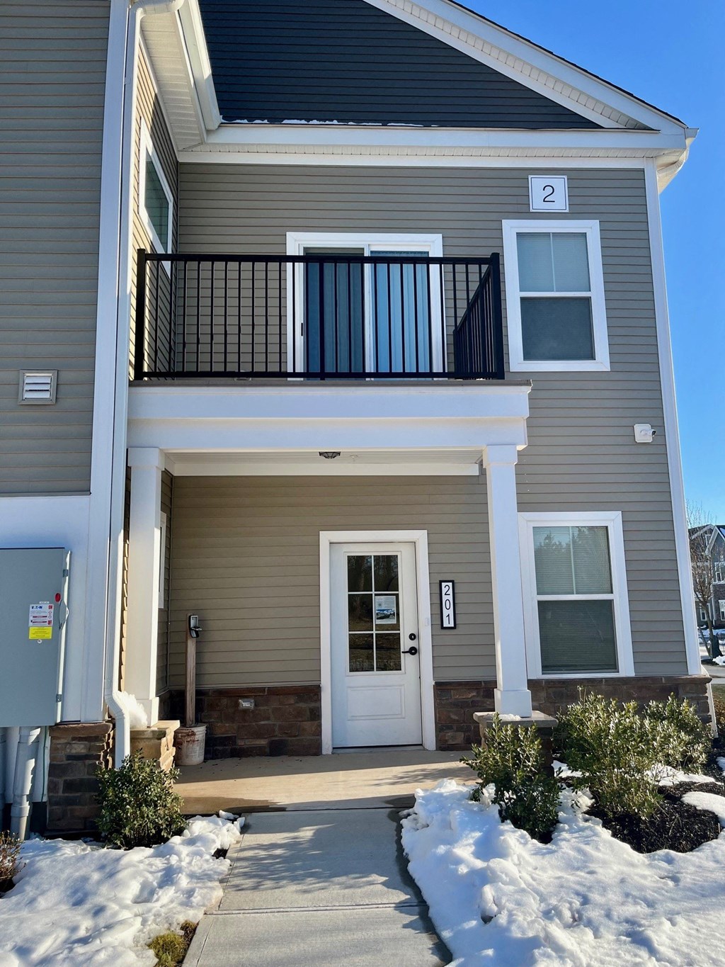 the front of a house with a white door and a balcony