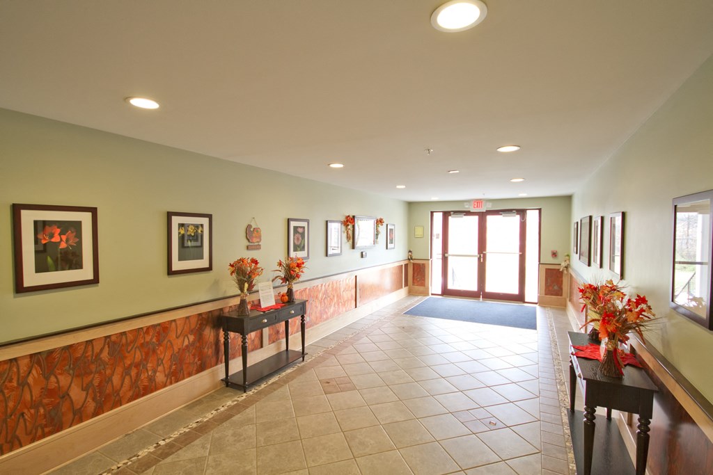 a long hallway with flowers on the tables and a door to a lobby