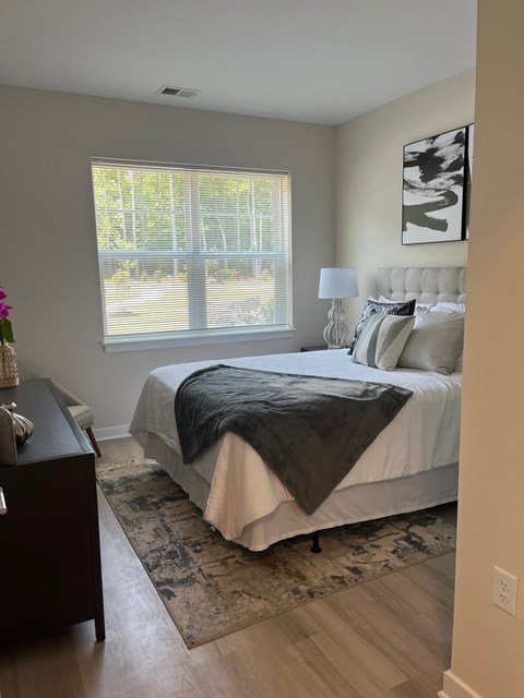 A bedroom with a bed, nightstand, and window.