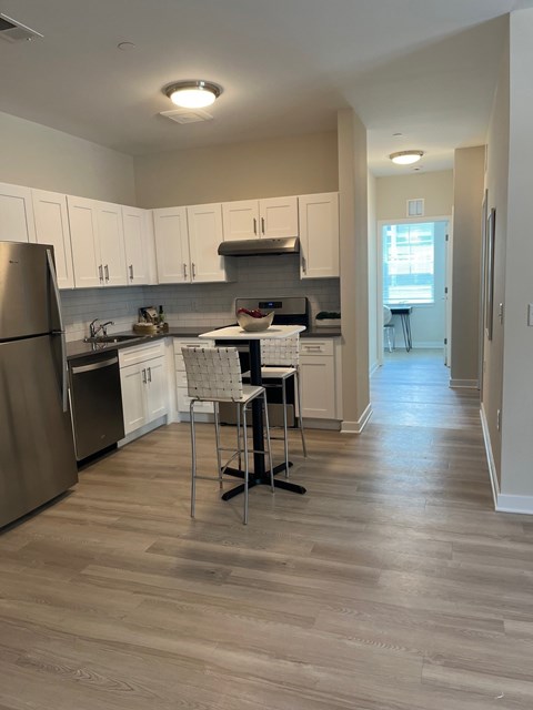 A kitchen with a refrigerator, sink, and a dining table with two chairs.