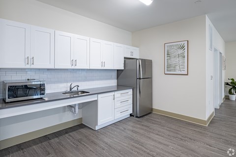 A kitchen with white cabinets and a grey refrigerator.