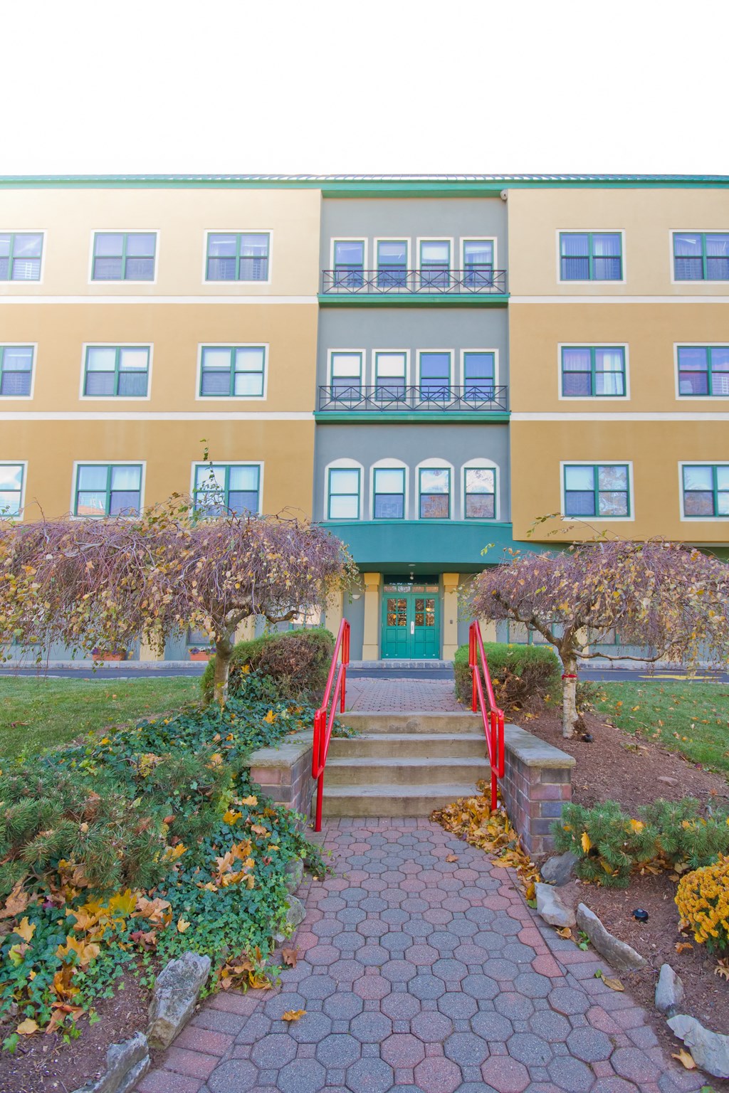 a pathway in front of a building with a red staircase