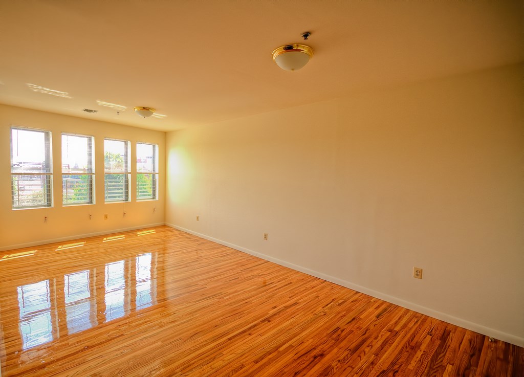 the living room of an empty house with wood floors and a ceiling fan