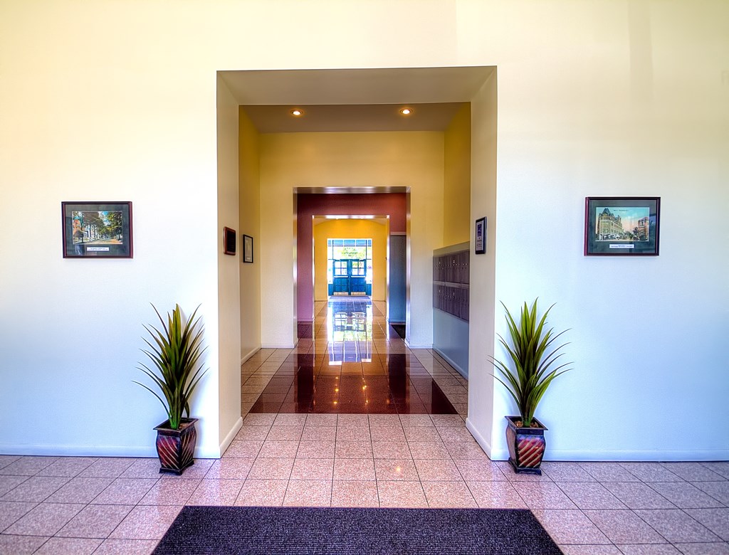 the lobby of a hotel with a long hallway with columns and plants