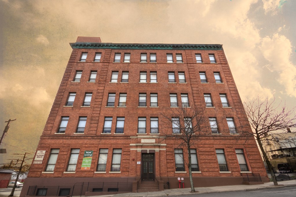 a tall red brick building with a cloudy sky in the background