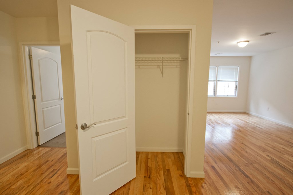 an empty bedroom with a closet and a hard wood floor