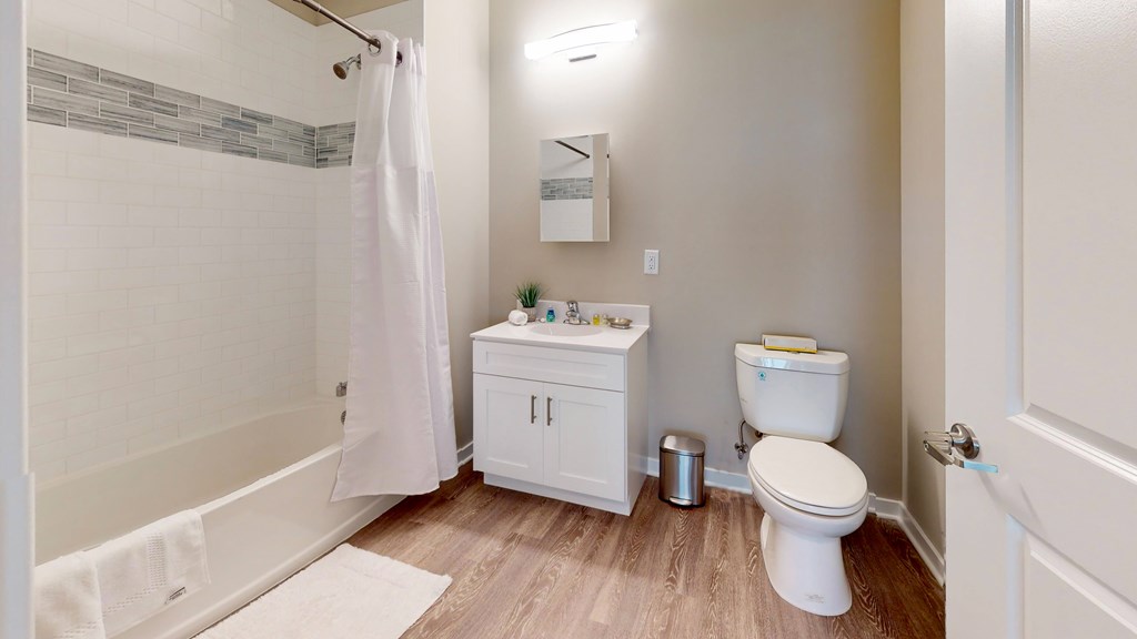 A white bathroom with a toilet, sink, and shower.