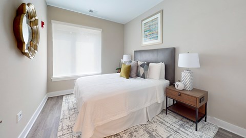 A bedroom with a large bed, a nightstand, and a mirror on the wall.