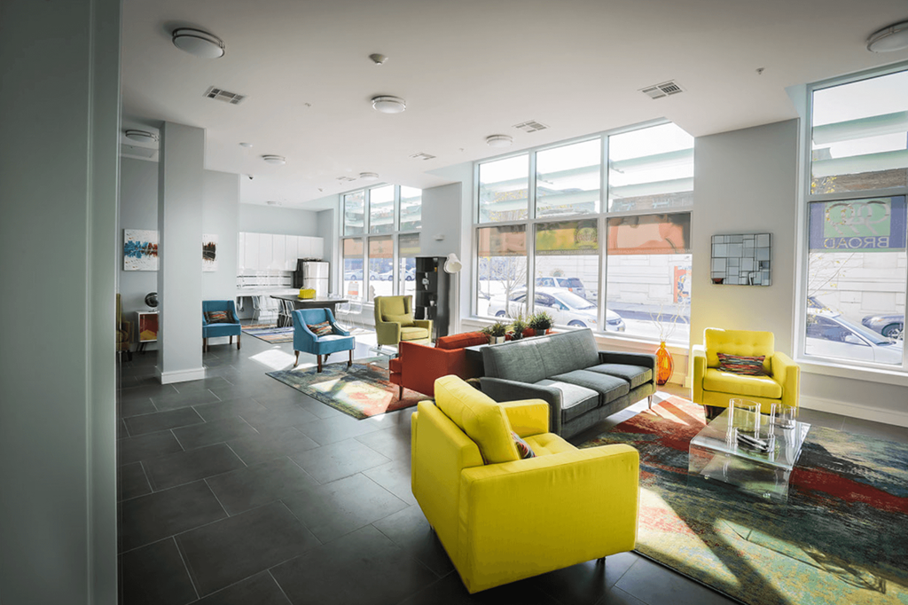 a living room with yellow and gray furniture and large windows