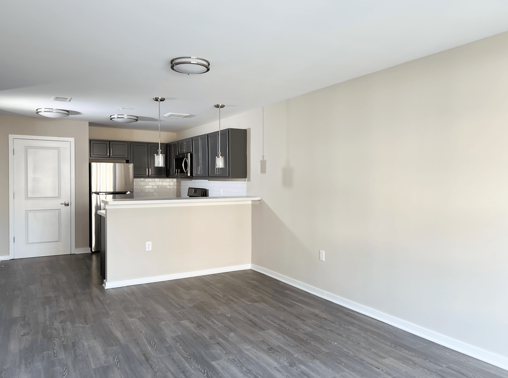 an empty living room and kitchen with a white wall and wood floor