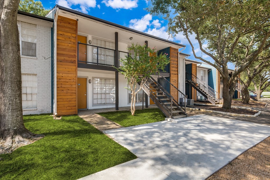 a house with a sidewalk and trees in front of it