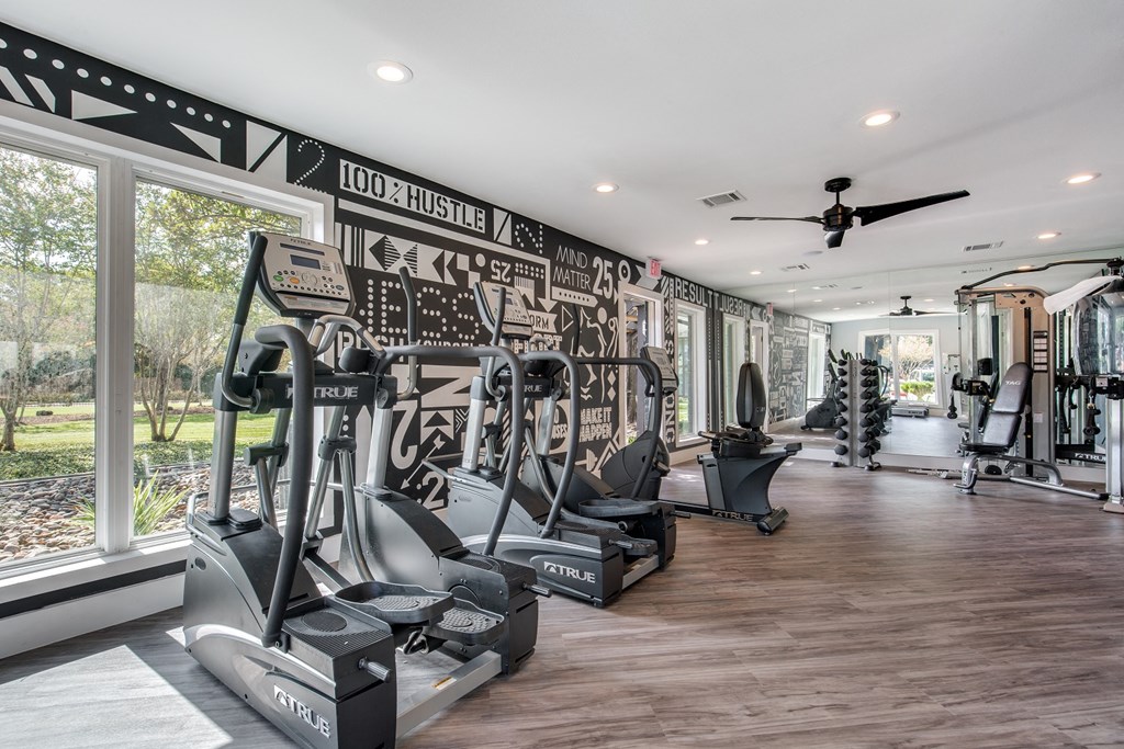 a home gym with cardio machines and a large window