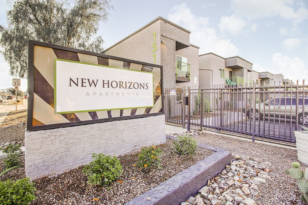 new horizons apartments sign in front of a building with a fence and a car