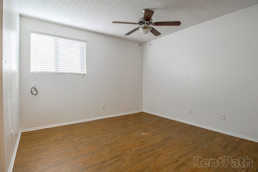 a bedroom with a ceiling fan and a wood floor