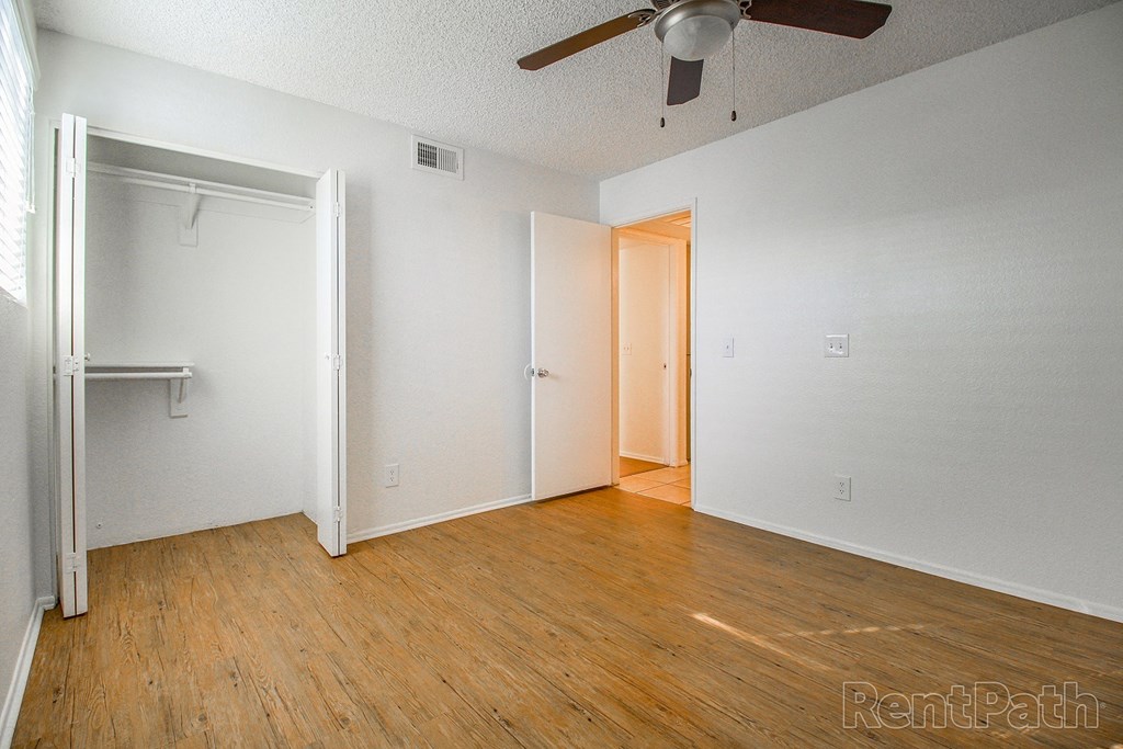 a bedroom with wood floors and white walls and a ceiling fan