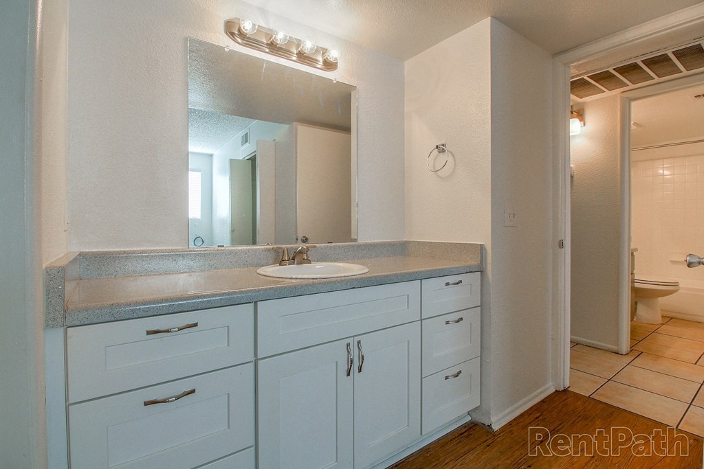 a bathroom with white cabinets and a sink and a mirror