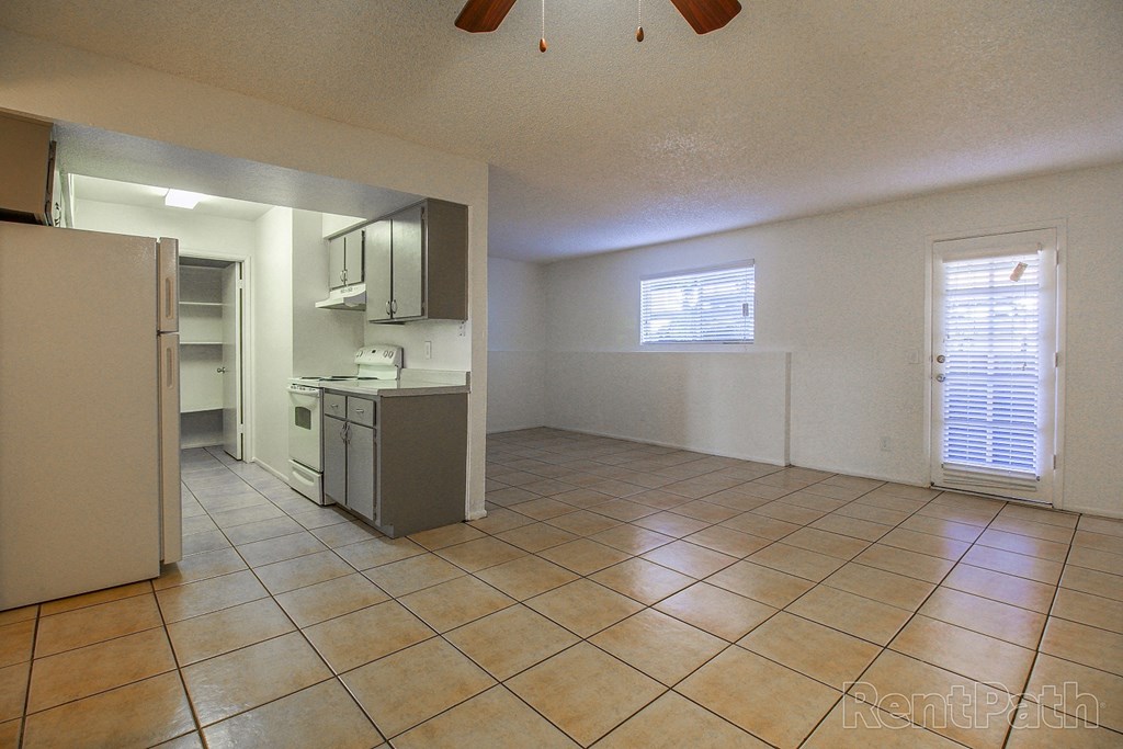 an empty kitchen and living room with a refrigerator and a sink