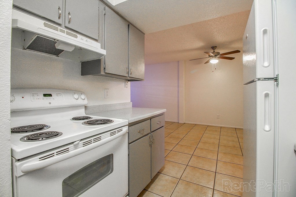 a kitchen with a stove and a refrigerator and a ceiling fan