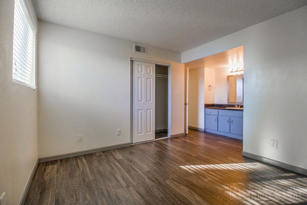 an empty living room and kitchen with wood flooring and white walls