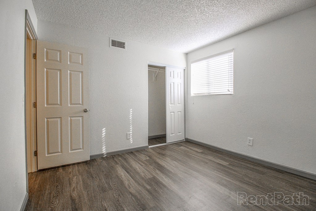 a bedroom with white walls and wood floors and a door