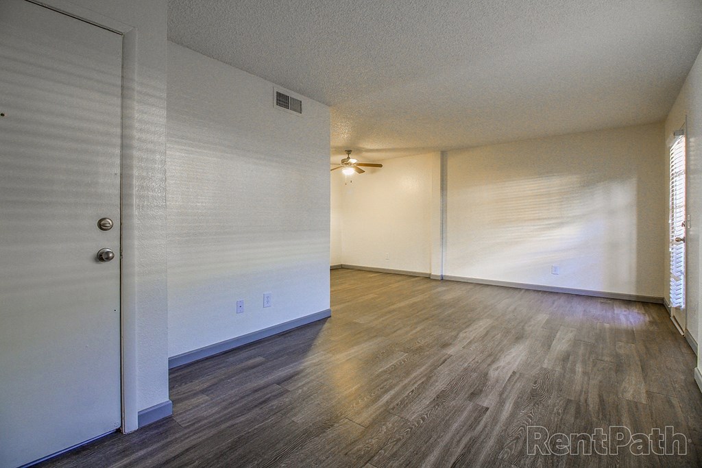 an empty living room with wood floors and white walls
