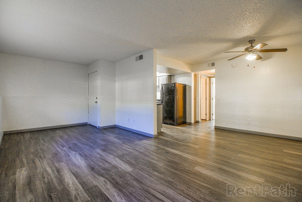 an empty living room with wood flooring and a ceiling fan