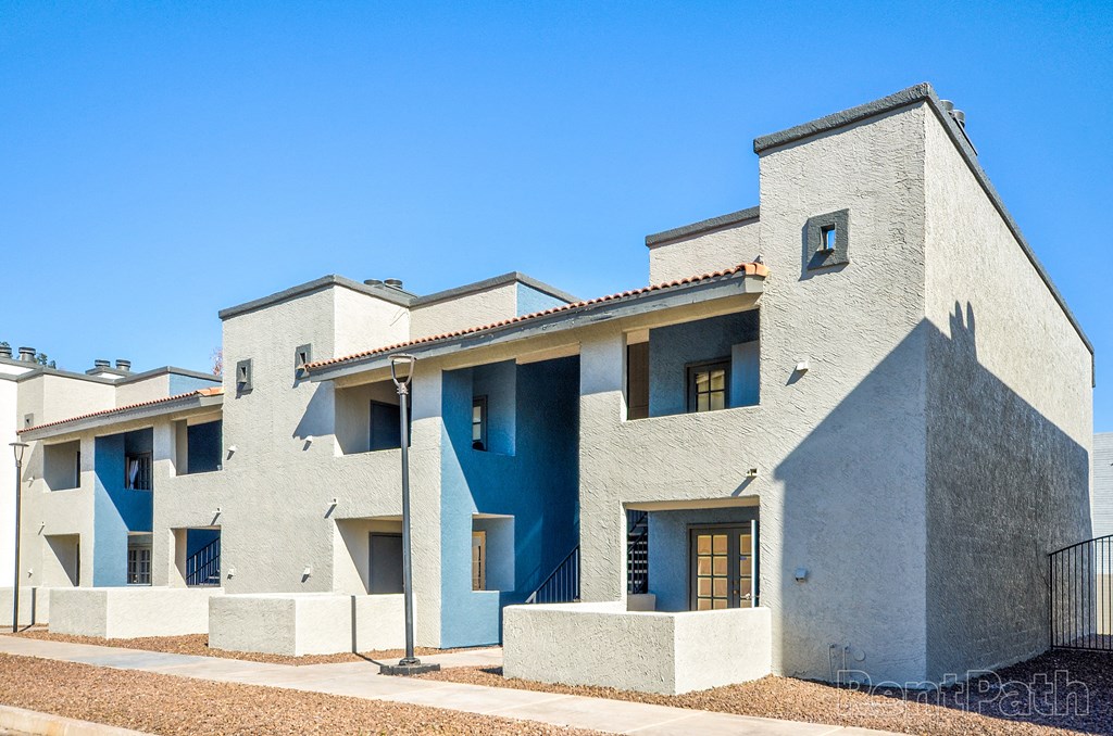 a group of white buildings with blue doors and a blue sky