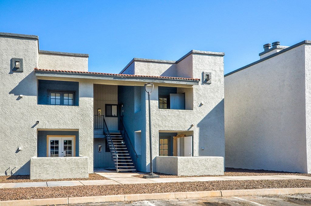 the front of a white building with stairs and a blue sky