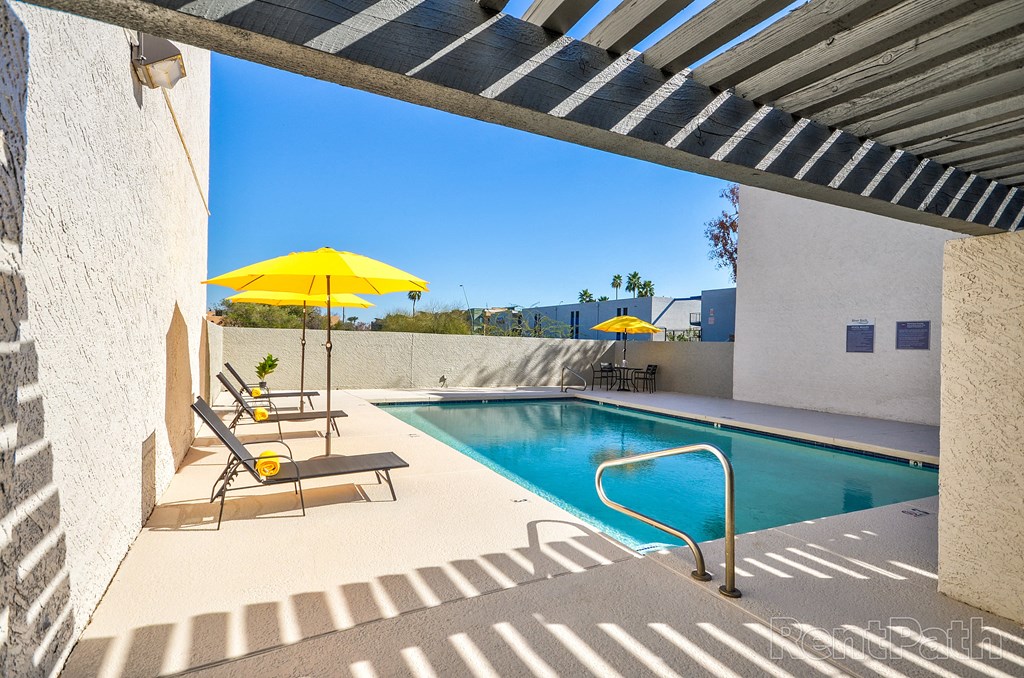 a swimming pool in the backyard of a house with a yellow umbrella
