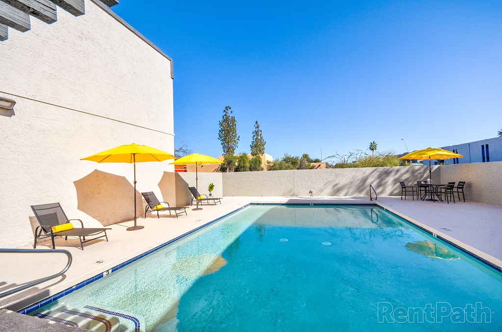 a pool with chairs and umbrellas next to a building