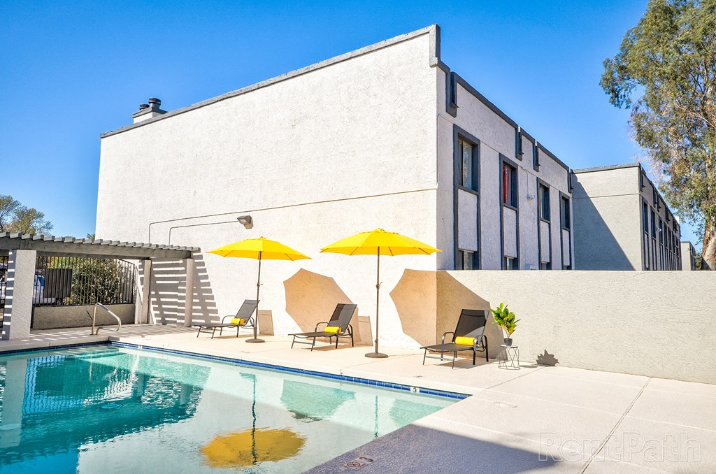 a swimming pool with chairs and umbrellas in front of a building