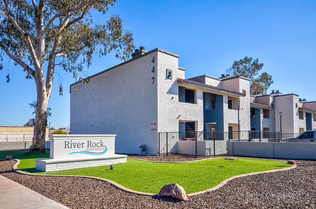 an apartment building with a river rock sign in front of it
