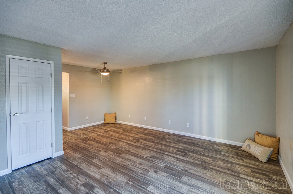 an empty living room with wood flooring and a white door