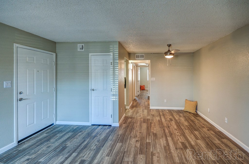 an empty living room with a hard wood floor and white doors