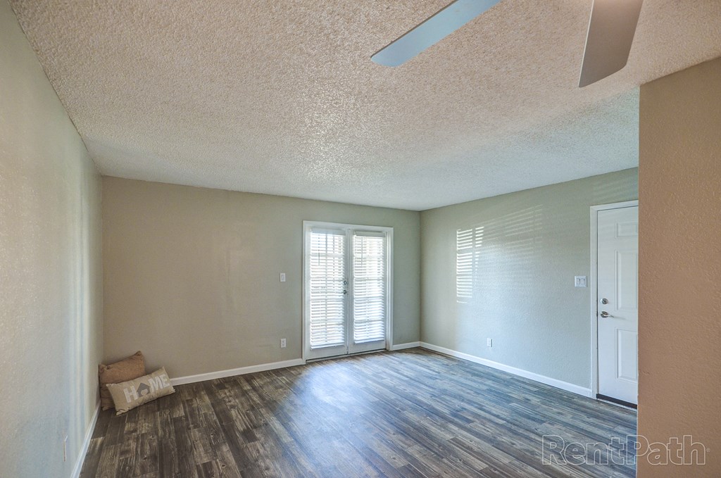 an empty living room with wood flooring and a sliding glass door
