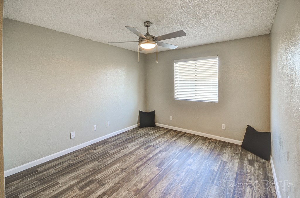 an empty living room with wood floors and a ceiling fan