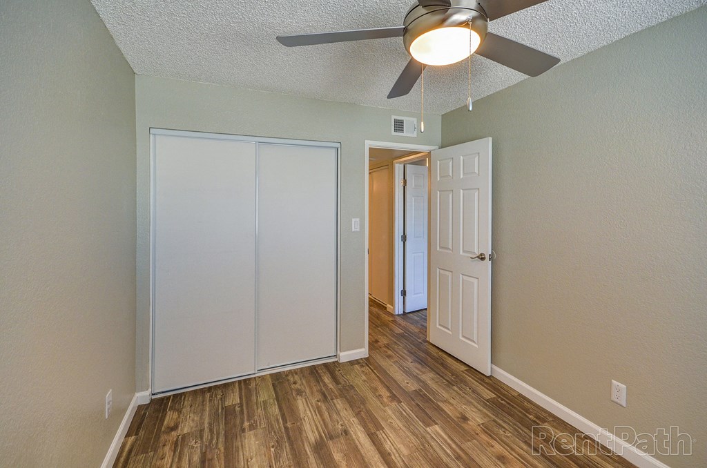 a bedroom with a ceiling fan and a door to a closet
