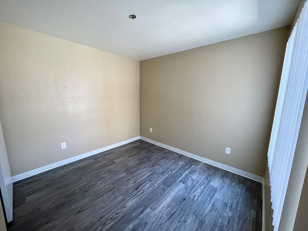 a bedroom with hardwood floors and beige walls