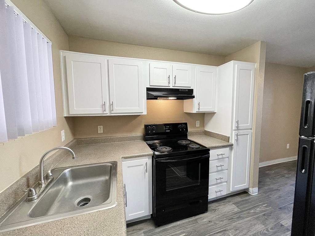 a kitchen with white cabinets and black appliances